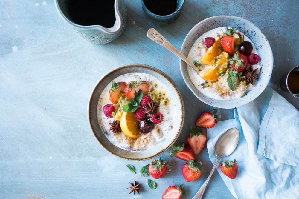 Selbstfürsorge Tipps - zwei Schalen mit Porridge, frischen Früchten